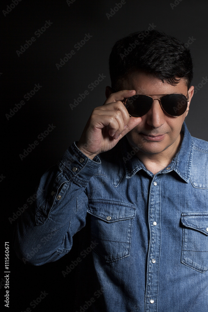Fototapeta premium Portrait of man in Blue jean shirt with sunglasses on black back