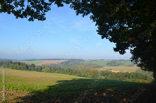 Woman and girl walking on trail through rural landscape with meadows and fields on rolling hills in Wallonia on sunny autumn day  Durnal  Yvoir