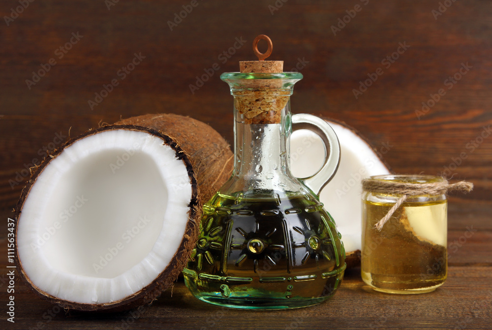 cut the coconut and coconut oil in a small glass jar on a brown wooden background cut the coconut and coconut oil in a small glass jar on a brown wooden background