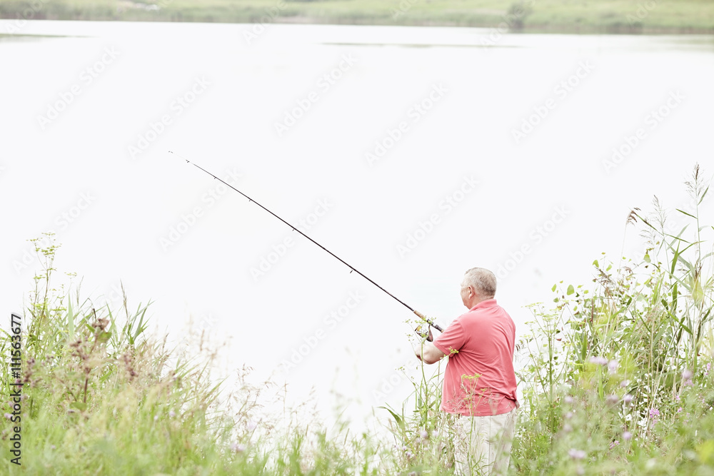 Mature angler catching fish on lake