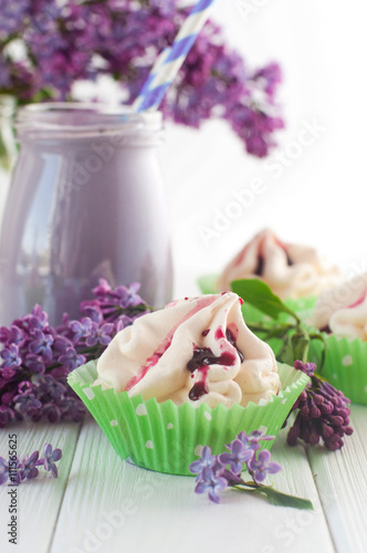 Meringue cake near bilberry milkshake and lilac flowers