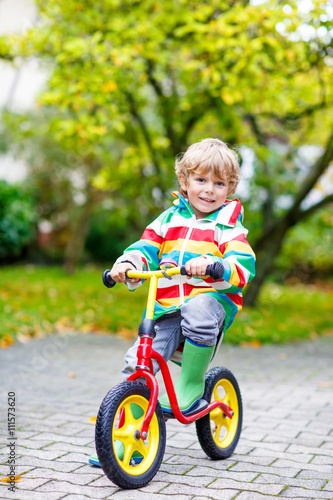 Fototapeta Naklejka Na Ścianę i Meble -  kid boy driving on bicycle on rainy day outdoors