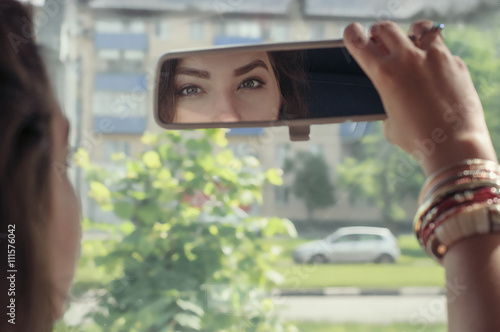 Woman looking at her reflection in the rearview