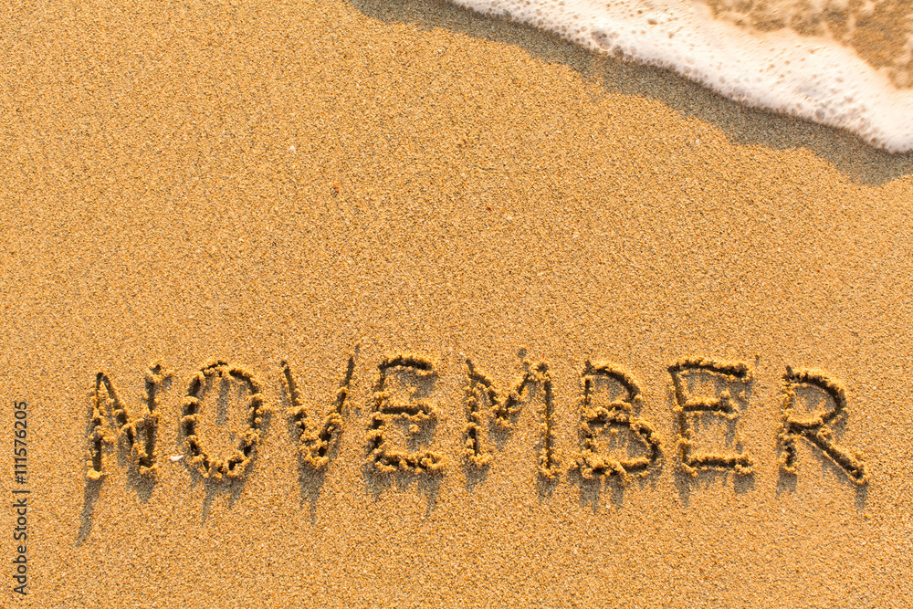Fototapeta premium November - written by hand on a golden beach sand.