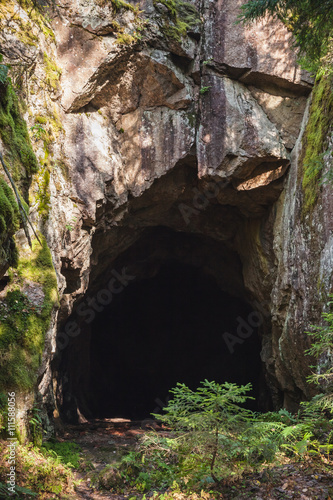 Entrance to dark cave in the rock, vertical