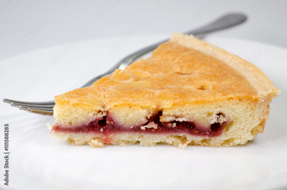 Slice of bakewell tart on plate with fork Slice of bakewell tart on plate with fork