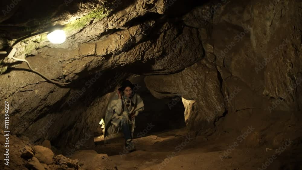 A young woman is standing inside a rock cave A young woman is standing inside a rock cave