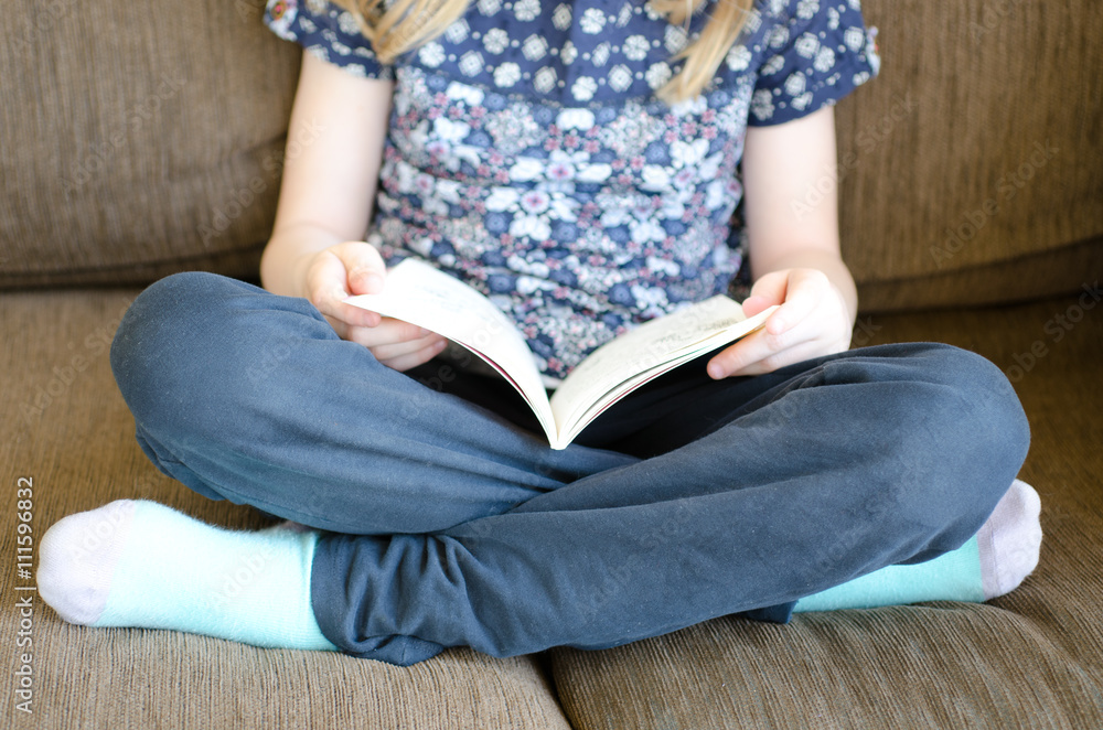 Fototapeta premium Little girl sitting on chair reading