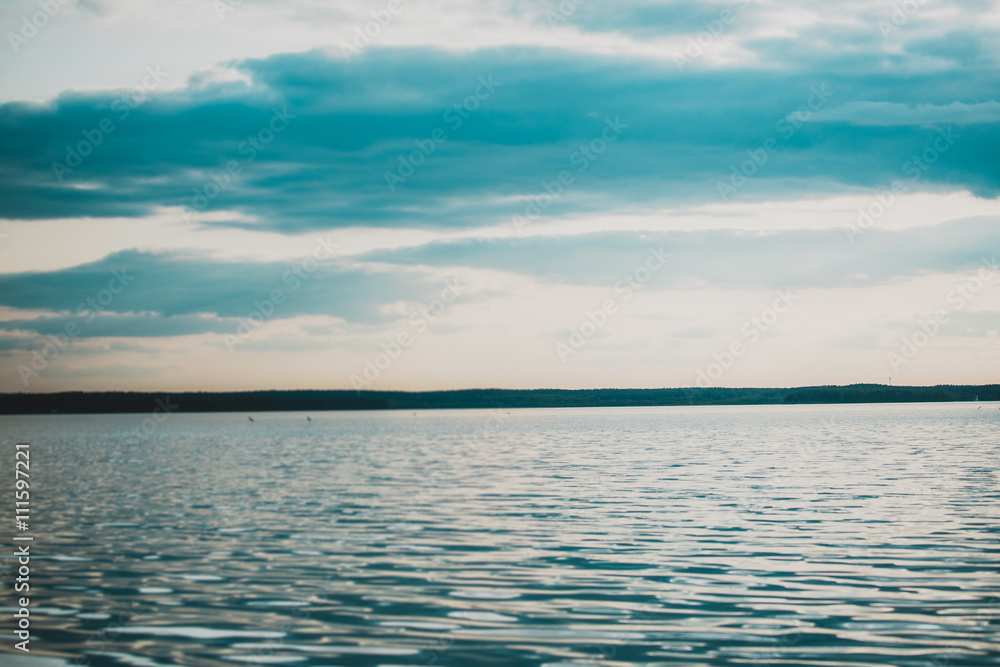 Picturesque view of a river and the blue sky. Cloudy day with sun rays through the sky. Picturesque view of a river and the blue sky. Cloudy day with sun rays through the sky.