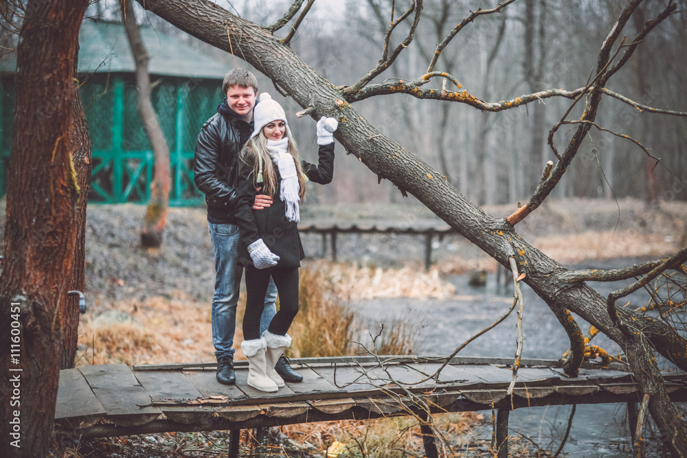 Beautiful young couple posing near lake and forest autumn. Woman in white gloves and cap. Beautiful young couple posing near lake and forest autumn. Woman in white gloves and cap.