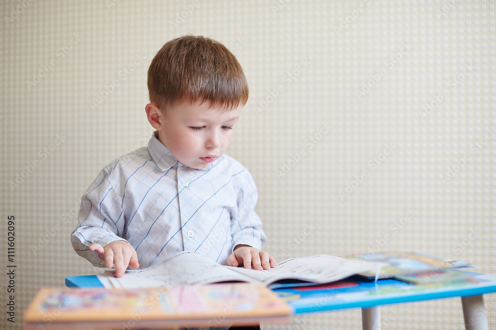 little boy sitting at the desk and reading a book little boy sitting at the desk and reading a book