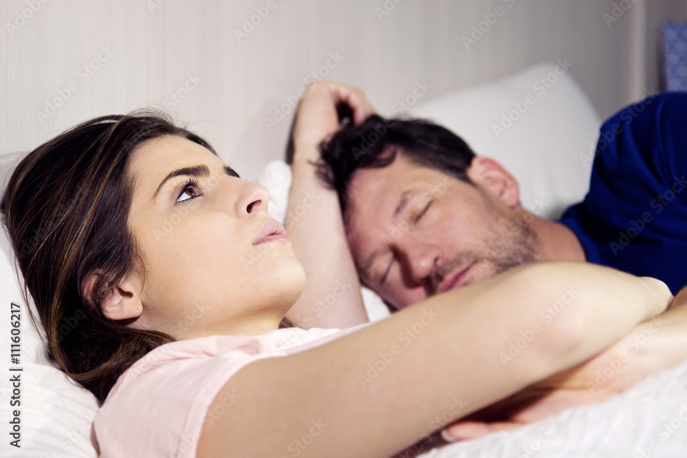Woman in bed with boyfriend thinking about relationship while the man is sleeping Woman in bed with boyfriend thinking about relationship while the man is sleeping