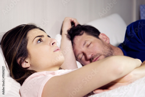 Woman in bed with boyfriend thinking about relationship while the man is sleeping