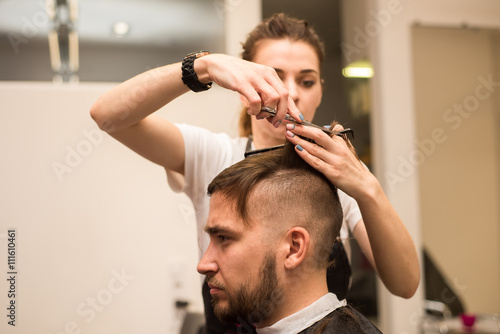 young man cuts hair in the barber shop