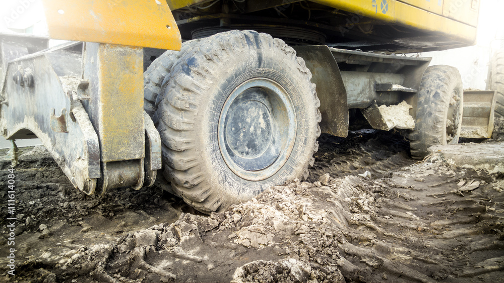 Excavator wheels covered with mud on building site