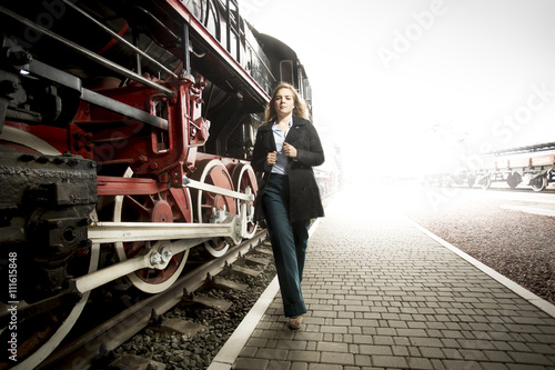 Toned photo of elegant woman walking on railroad platform past o