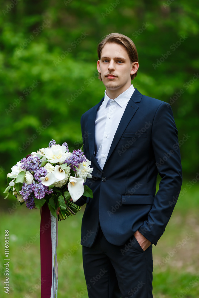 Young beautiful groom standing and holding wedding bouquet Young beautiful groom standing and holding wedding bouquet