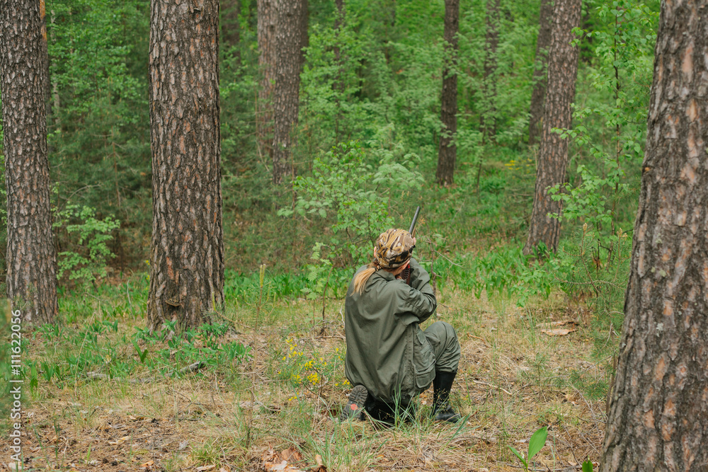 Woman hunter with a gun. Hunting in the woods.