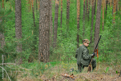 Woman hunter with a gun. Hunting in the woods.
