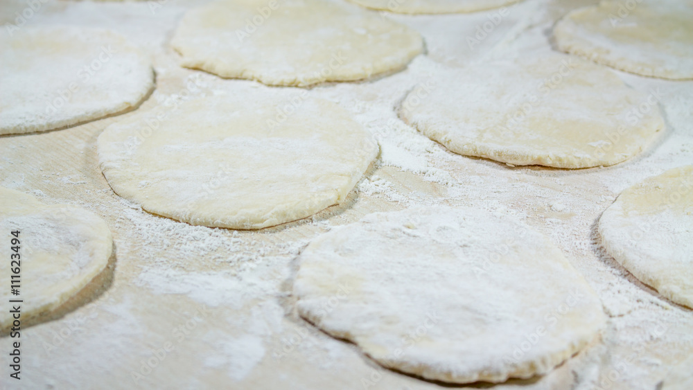 round shape of the dough with flour on the table