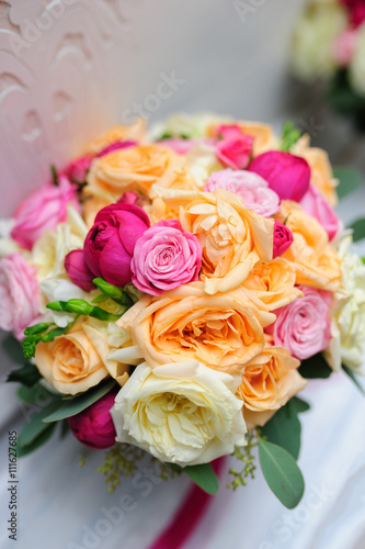 Beauty of colored flowers. Bridal accessories. Close-up bunch of florets. Details for marriage and for married couple. Wedding bouquet with roses and orchids on the white background