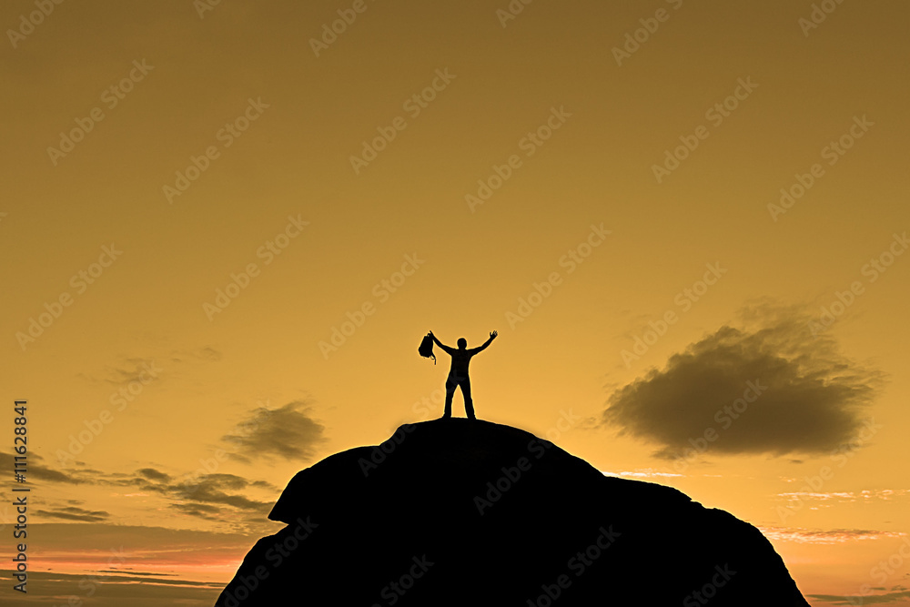 Силуэт человека на вершине горы на огненно-оранжевом фоне поднятые руки вверх держащий в руках рюкзак