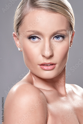 Portrait of beautiful blond model with blue eyes, on grey background