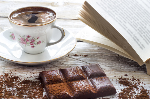 Turkish coffee with slices of chocolate and book on the wooden table  photo