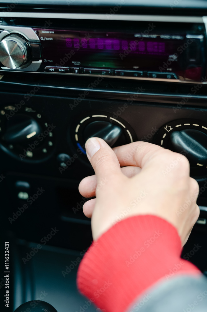 Closeup on female driver turning car air conditioner knob