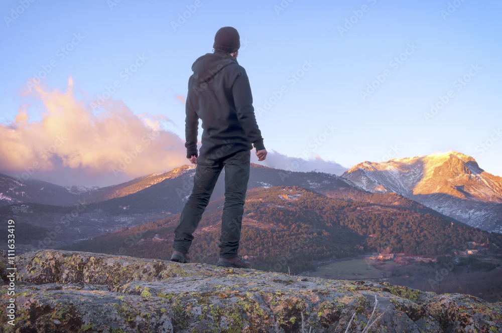 Man on top watching a beautiful sunrise in the sunny snowy mount