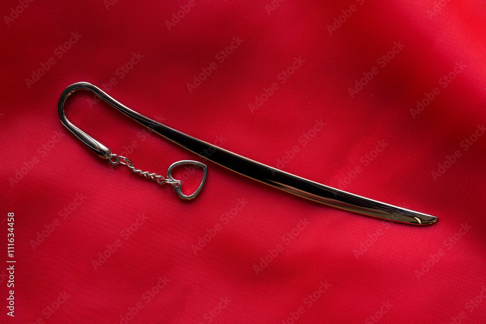 metal bookmark with heart symbol on delicate red silk background metal bookmark with heart symbol on delicate red silk background