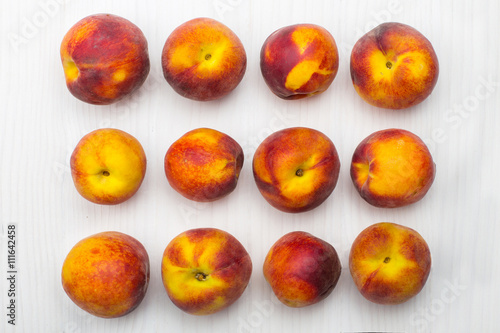 Ripe peaches lying on white wooden surface, top view