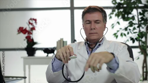 A mature doctor sitting in his office acting goofy until he is caught behaving in such an inept manner.