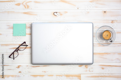 Espresso next to a laptop and stationery objects on a white wooden table