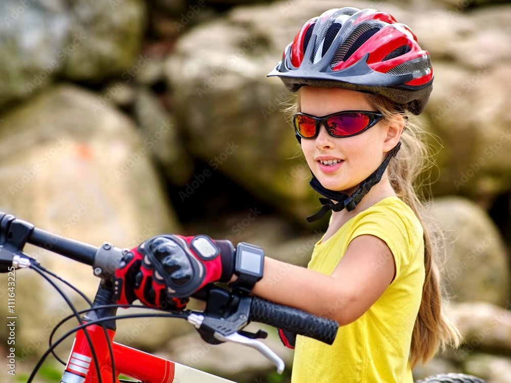 Naklejka premium Bikes bicyclist girl. Girl with smart watch rides bicycle into mountains. Girl wearing helmet and gloves on bicycle in mountaineering . Mountaineering is good for health. 