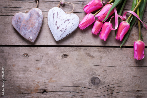 Bright pink spring tulips and two decorative hearts