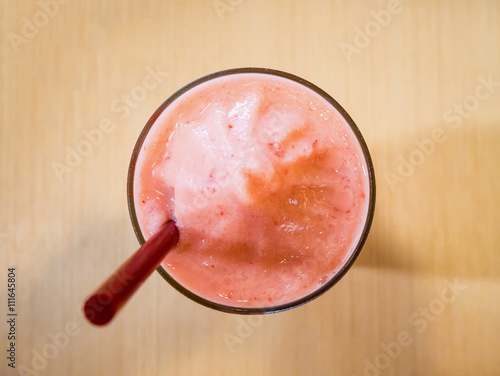 Strawberry smoothie in glass, on wood table