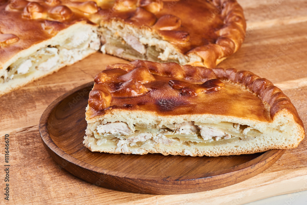 A piece of pie with chicken filling on a wooden plate A piece of pie with chicken filling on a wooden plate