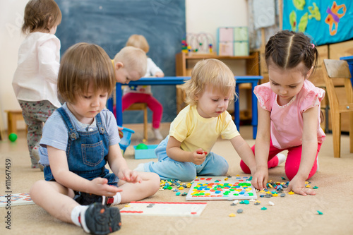 Tableau sur toile kids or children playing mosaic game in kindergarten room
