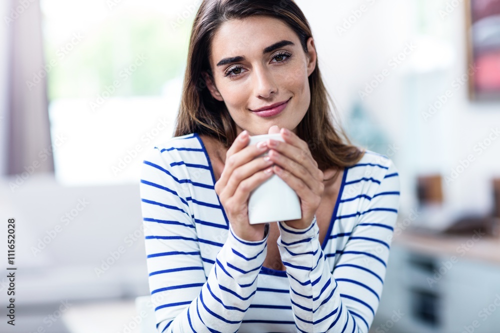 Portrait of beautiful young woman holding mug at home