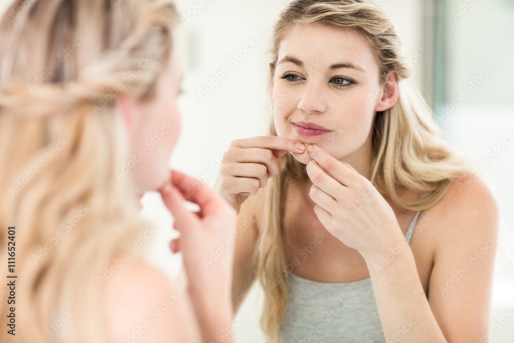 Concerned young woman looking in mirror Concerned young woman looking in mirror