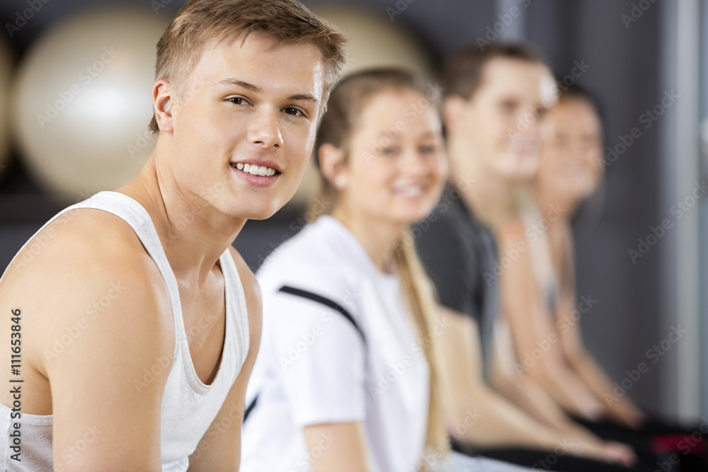 Man Smiling While Sitting With Friends In Gym Man Smiling While Sitting With Friends In Gym
