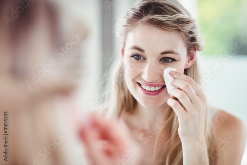 Happy young woman applying blush