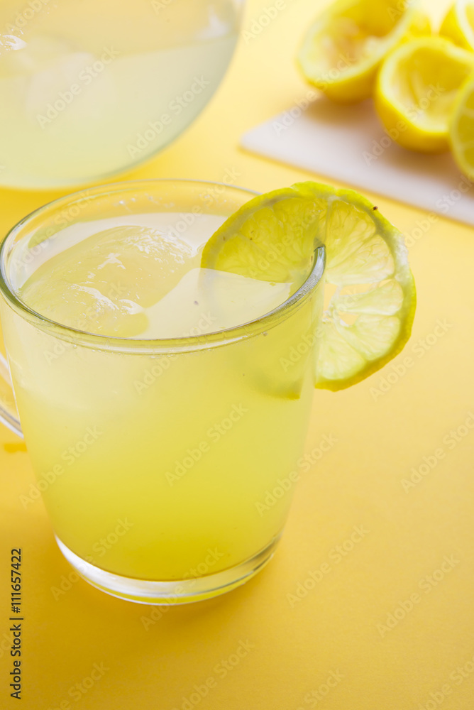 Water and lemon in yellow background Water and lemon in yellow background