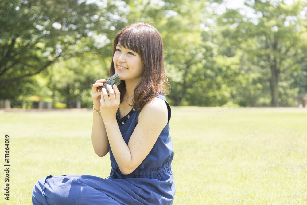 公園でおにぎりを食べる女性