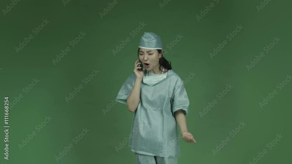 young asian adult woman doctor surgeon isolated on green-screen background upset talking cell phone young asian adult woman doctor surgeon isolated on green-screen background upset talking cell phone