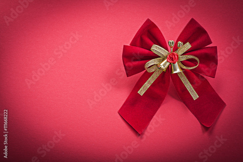 Christmas bow with bells on red background holidays concept
