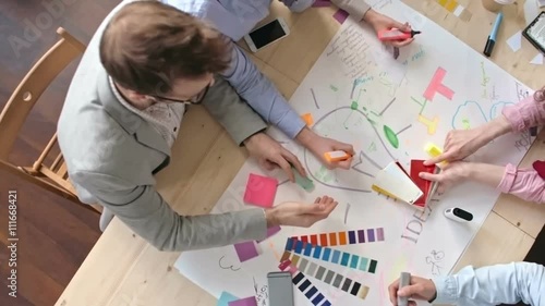 Top view of creative young team of designers brainstorming to generate ideas in meeting and using color swatch, shot on Sony NEX 700  