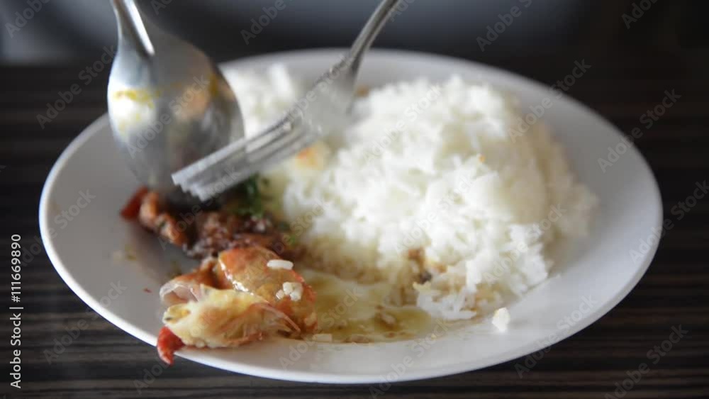 Asian man eating the rice and Thai spicy shrimp soup (Tom Yum Kung) with spoon and fork closeup on the dish closeup. Asian man eating the rice and Thai spicy shrimp soup (Tom Yum Kung) with spoon and fork closeup on the dish closeup.