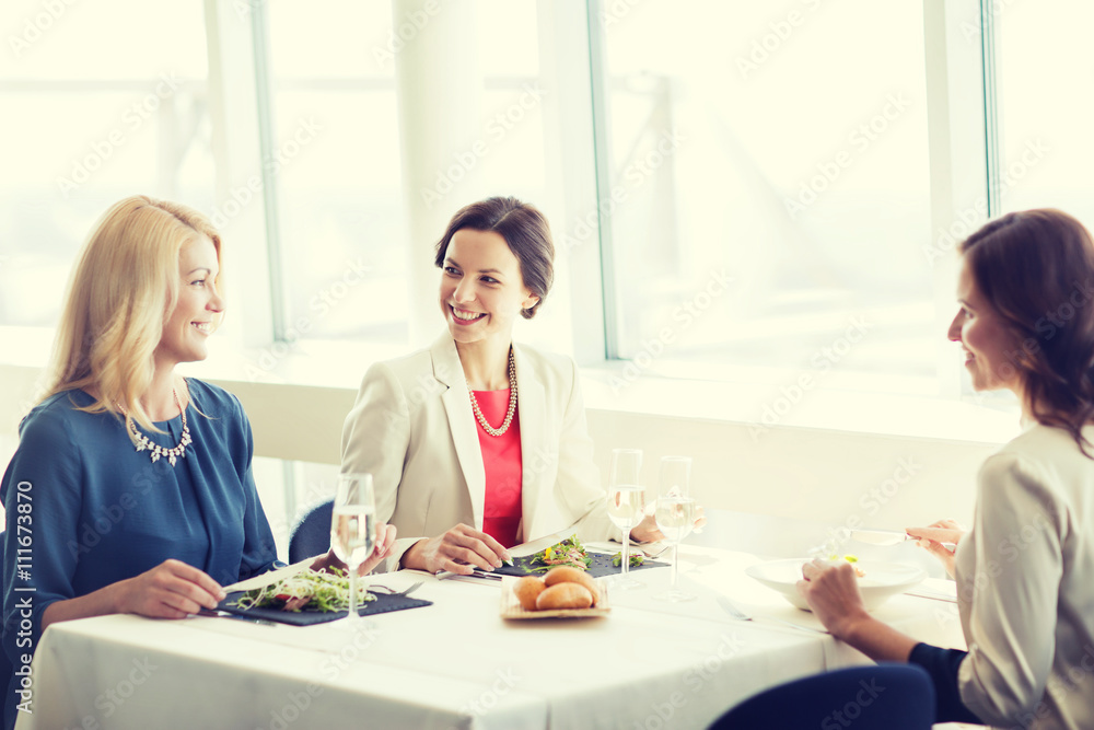 happy women eating and talking at restaurant